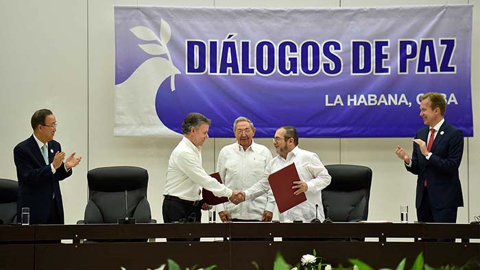  
Colombian president Juan Manuel Santos (second from left) and Rodrigo Londono Echeverri (second from right), shake hands during a presentation about the ceasefire agreement. (Presidency of the Republic of Colombia) 
